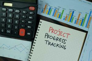 Project Progress Tracking write on a book isolated on Wooden Table. photo