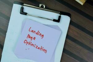 Concept of Landing Page Optimization write on sticky notes isolated on Wooden Table. photo