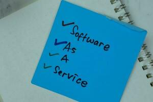 Software As A Service write on sticky notes isolated on Wooden Table. photo