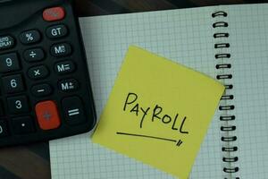 Concept of Payroll write on sticky notes isolated on Wooden Table. photo