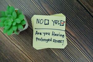 Concept of Are you having prolonged stress Yes write on sticky notes isolated on Wooden Table. photo