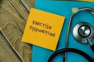 Concept of Erective Dysfunction write on sticky notes with stethoscope isolated on Wooden Table. photo