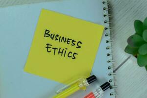 Concept of Business Ethics write on a book isolated on Wooden Table. photo