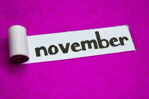 November text, Inspiration, Motivation and business concept on purple torn paper photo