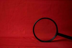 Magnifying glass on red background photo