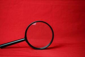 Magnifying glass on red background photo