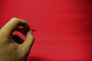 Man hand with red pen writing on red background photo