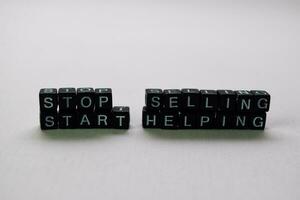 Stop selling start helping on wooden blocks. Motivation and inspiration concept photo