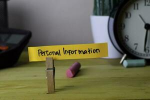 Personal Information. Handwriting on sticky notes in clothes pegs on wooden office desk photo