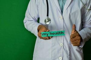 doctor standing on Green background. Hold the My Health paper text. Medical and healthcare concept. photo