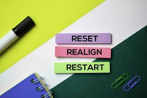 Reset. Realign. Restart text on sticky notes with office desk concept photo