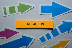 Take Action text on sticky notes isolated on office desk photo