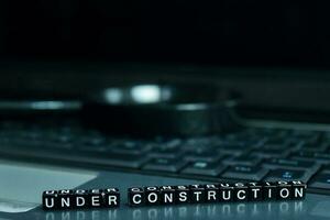 Under Construction text wooden blocks in laptop background. Business and technology concept photo