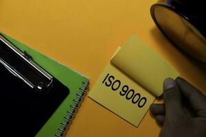 ISO 9000 write on sticky notes. Isolated on orange table background photo