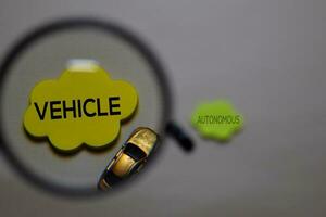 Vehicle or Autonomous write on a sticky note isolated on office desk. Selective focus on Vehicle text photo