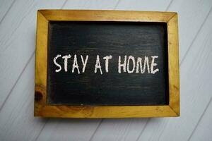 Stay At Home write on a chalkboard isolated on office desk. photo