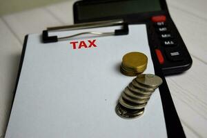 Tax write on paperwork on clipboard and the stack of coint. Finance or Tax Concept photo