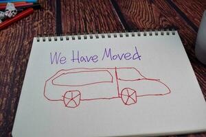 We Have Moved write on a book and drawing car Isolated on wooden table background photo