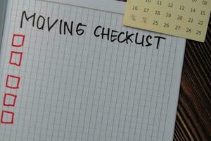 Moving Checklist write on a book. Supported by an additional services isolated on wooden table. photo