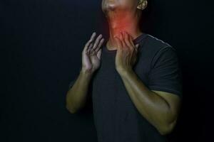 Young man thyroid gland by himself with red spot on black background. Medical or Healthcare concept photo