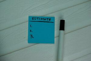 Estimated write on sticky notes Supported by an additional services isolated on office desk. photo