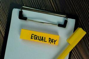 Equal Pay write on sticky notes isolated on Wooden Table. photo