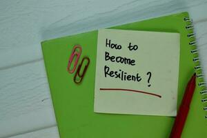 How to Become Resilient write on sticky note isolated on Wooden Table. photo