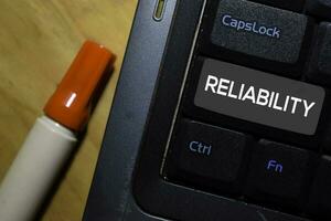 Reliability write on keyboard isolated on laptop background photo