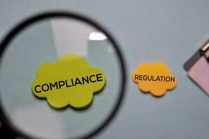 Compliance and Regulation write on a sticky note isolated on office desk. photo