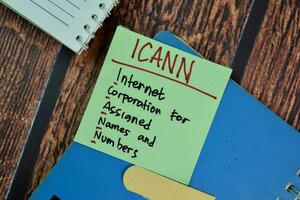 ICANN - Internet Corporation for Assigned Names and Numbers write on sticky notes isolated on Wooden Table. photo