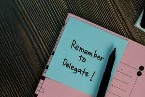 Remember to Delegate write on sticky notes isolated on Wooden Table. photo