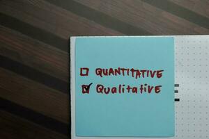 Quantitative and Qualitative write on sticky notes and supported by additional services write on a sticky notes isolated on Wooden Table. photo