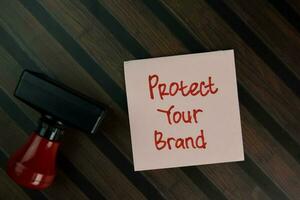 Protect Your Brand write on sticky notes isolated on Wooden Table. photo