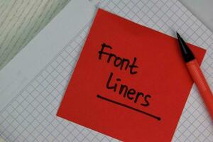 Front Liners write on sticky notes isolated on Wooden Table. photo