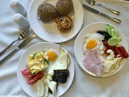 almuerzo. platos de huevos, jamón, queso y vegetales en mesa. estudio foto