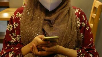 Young woman with face mask using smart phone at cafe video