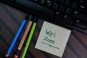 Wifi zone write on sticky notes isolated on Wooden Table. photo