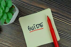 Guide write on sticky notes isolated on Wooden Table. photo