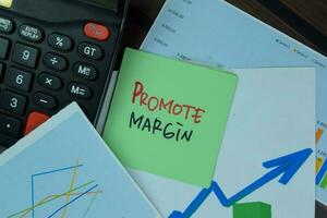 Promote Margin write on sticky notes isolated on Wooden Table. photo