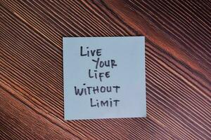 Live Your Life Without Limit write on sticky notes isolated on Wooden Table. photo