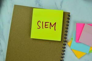 Concept of SIEM write on sticky notes isolated on Wooden Table. photo