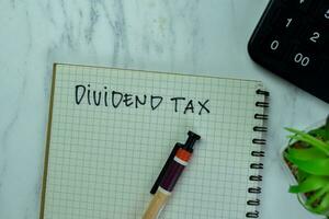 Concept of Dividend Tax write on a book isolated on Wooden Table. photo