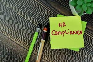 Concept of HR Compliance write on sticky notes isolated on Wooden Table. photo