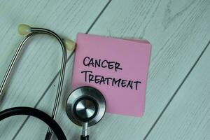 Concept of Cancer Treatment write on sticky notes isolated on Wooden Table. photo