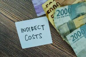 Concept of Indirect Costs write on sticky notes isolated on Wooden Table. photo