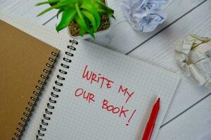 Write My Our Book write on a book isolated on Wooden Table. photo