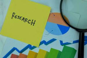 Concept of Research write on sticky notes with diagram or graph isolated on Wooden Table. photo