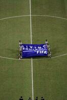 Soccer referee in gray shirt on field holding flag with text living football. Jakarta, Indonesia, August 1, 2022 photo