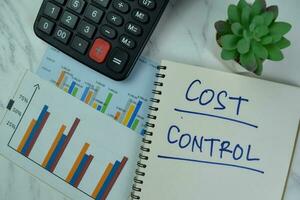 Cost Control write on a book isolated on Wooden Table. photo