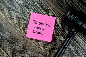 Concept of Concealed Caryy Laws write on sticky notes with gavel isolated on Wooden Table. photo